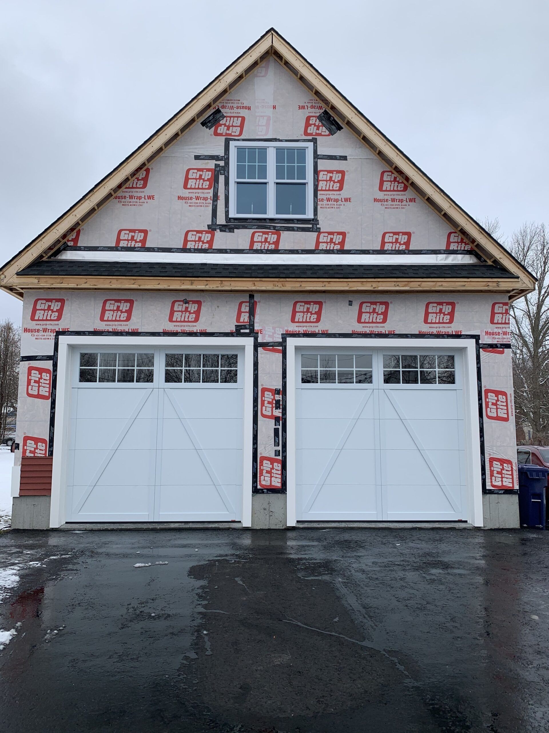 White garage doors, two car garage under construction, with small window above.