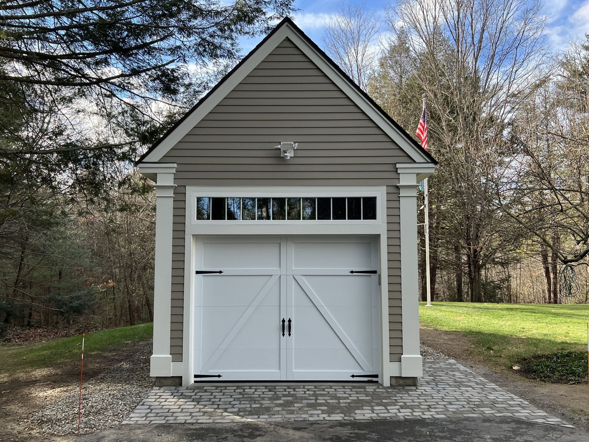 White garage doors with white trim, gray siding, and black hardware.