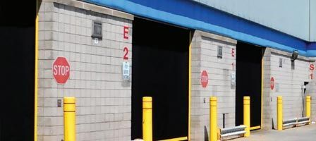 Warehouse loading dock doors with stop signs and yellow bollards.