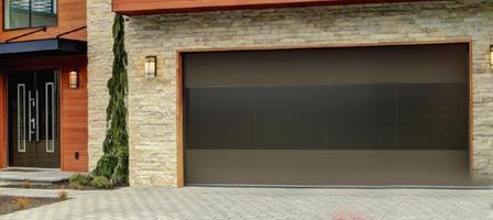 Modern home exterior with a dark garage door and a stone facade.