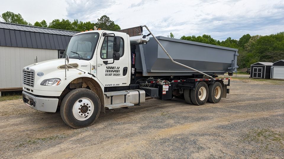 A dump truck is parked in a gravel lot in front of a building.