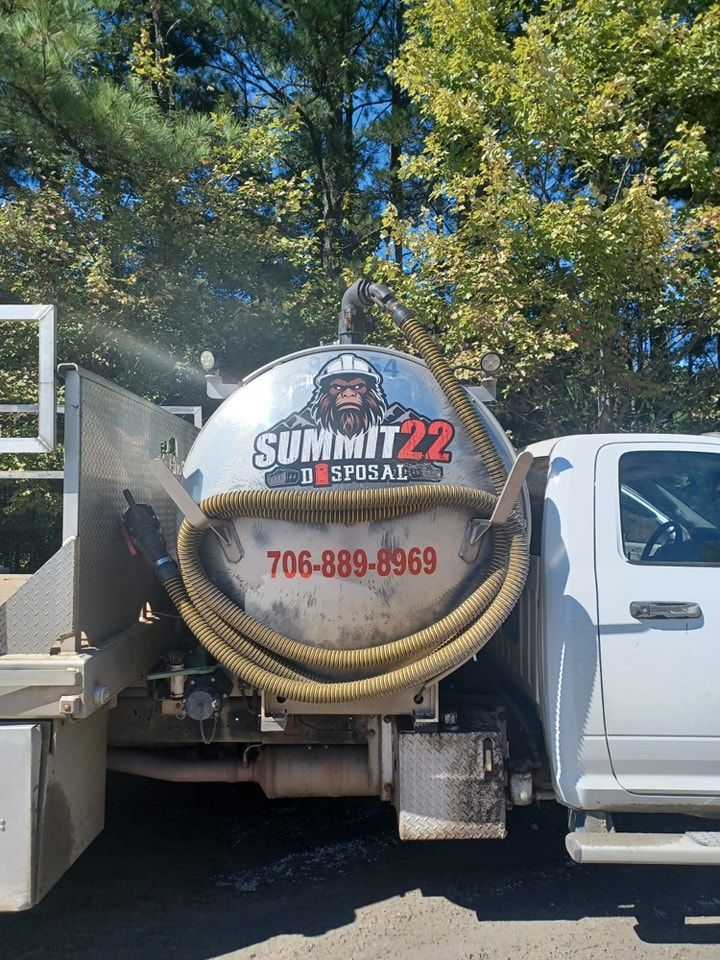 A vacuum truck is parked in a parking lot with trees in the background.