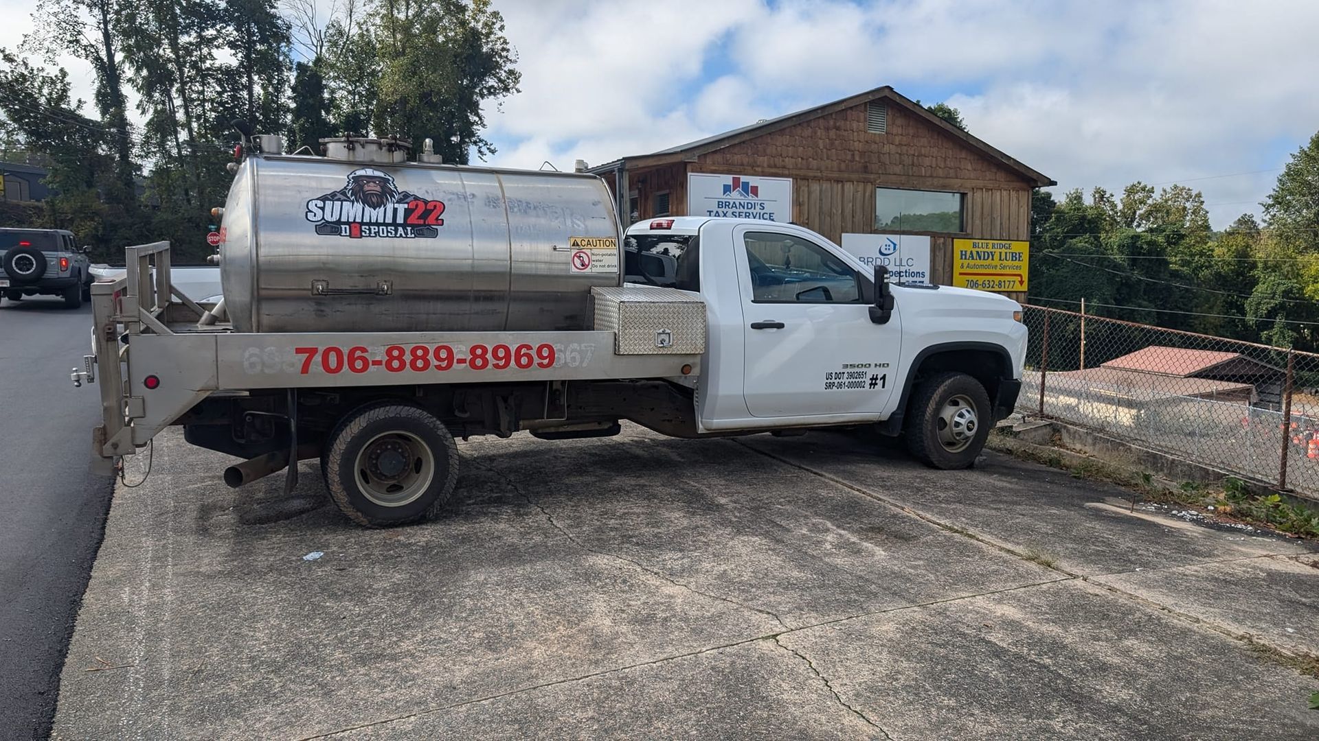 A white truck is parked on the side of the road in front of a building.