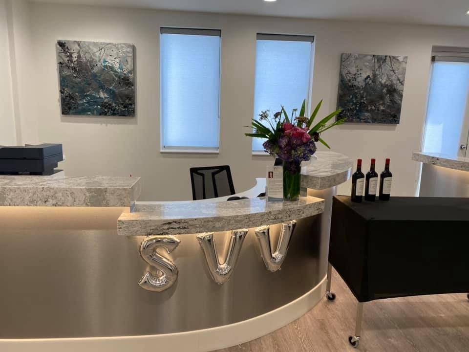 A reception area with a stainless steel counter and bottles of wine on a table.