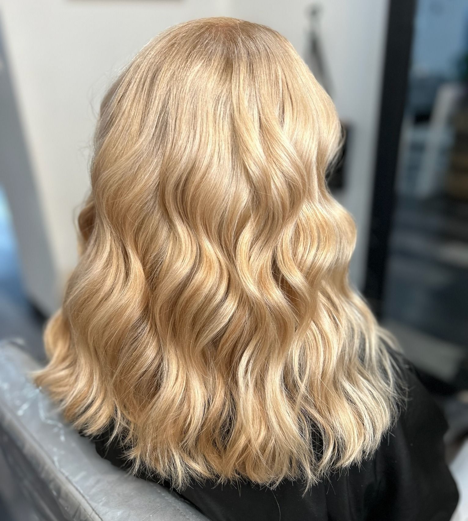 Wavy, light blonde hair styled on a person, the back view.