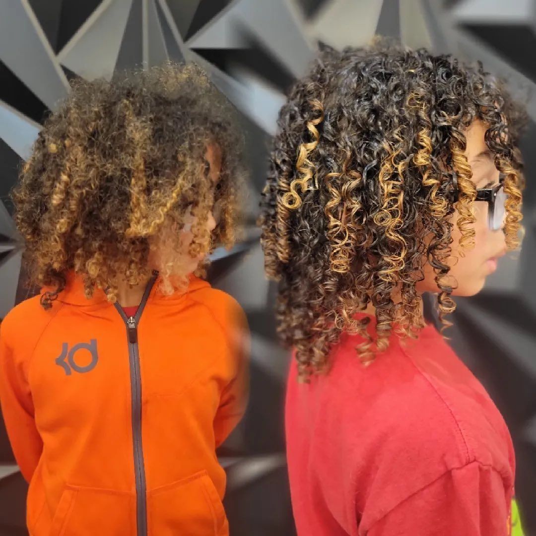 Two people with curly hair, one in an orange hoodie and the other in a red shirt. Both have light highlights.
