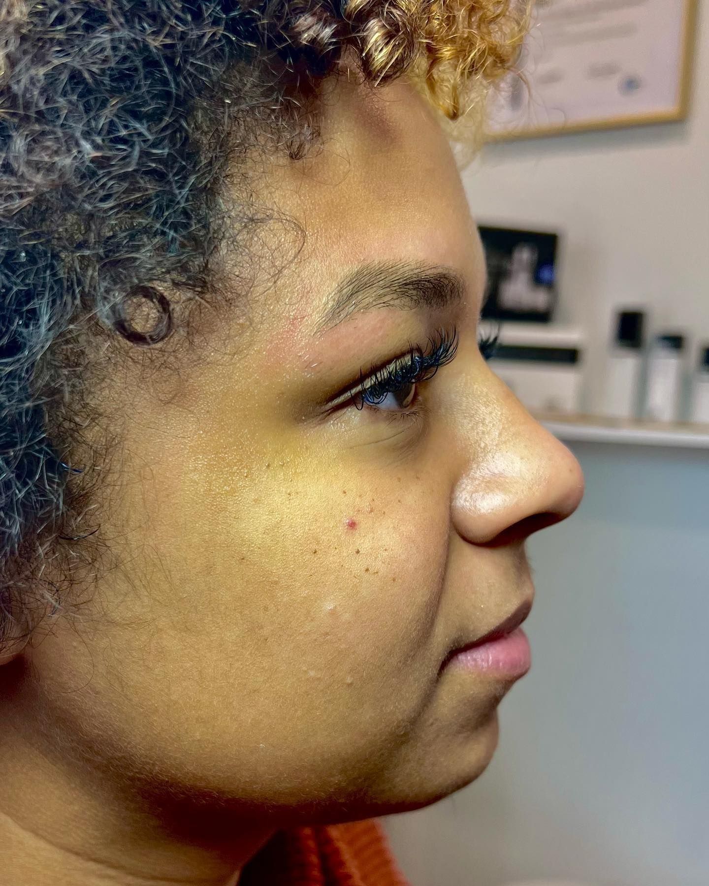 Profile view of a person with curly hair, light skin, and a thoughtful expression.