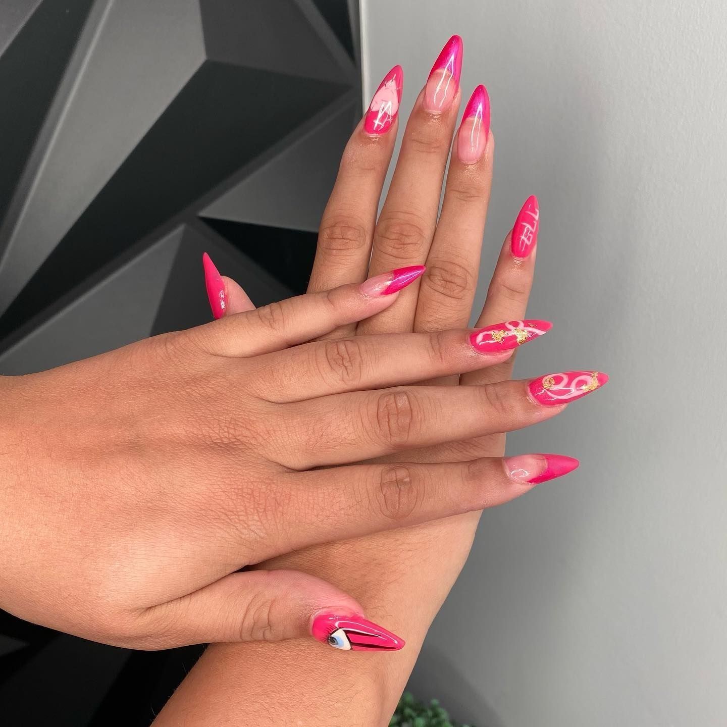 Hands with long, pointed pink and patterned gel nails.