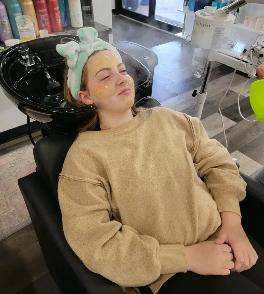 Person with a facial mask and headband, receiving a spa treatment