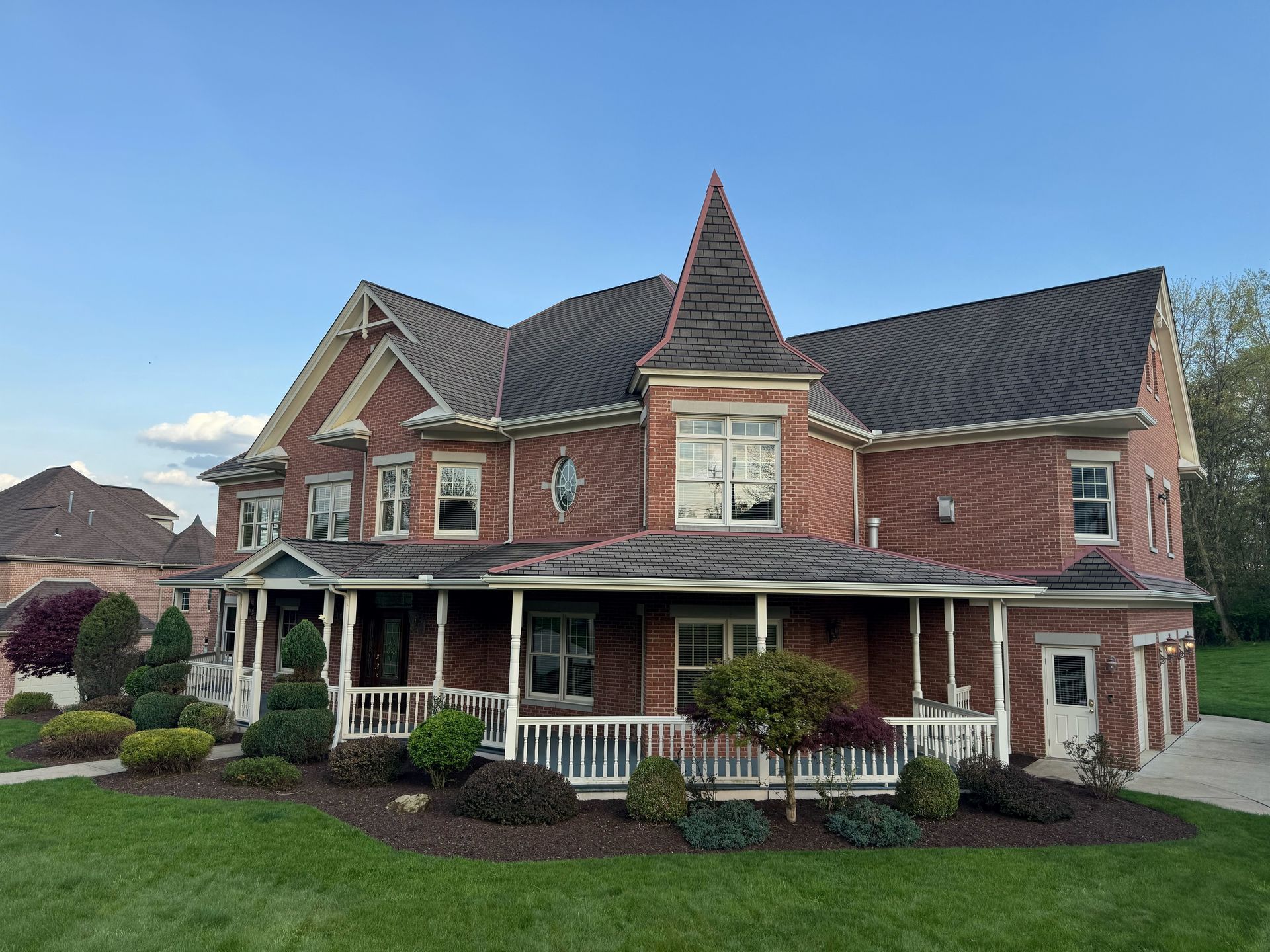 A large brick house with a large porch and a roof.