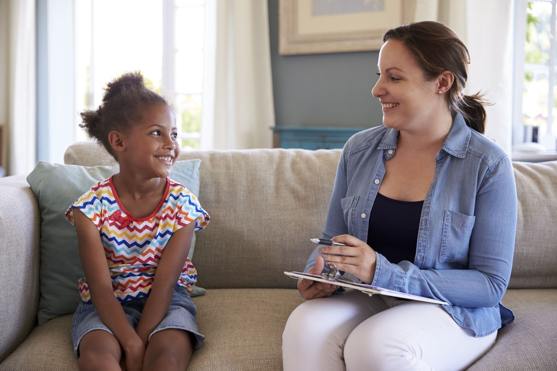 Couple smiling on blue sofa during therapy session with blonde therapist.