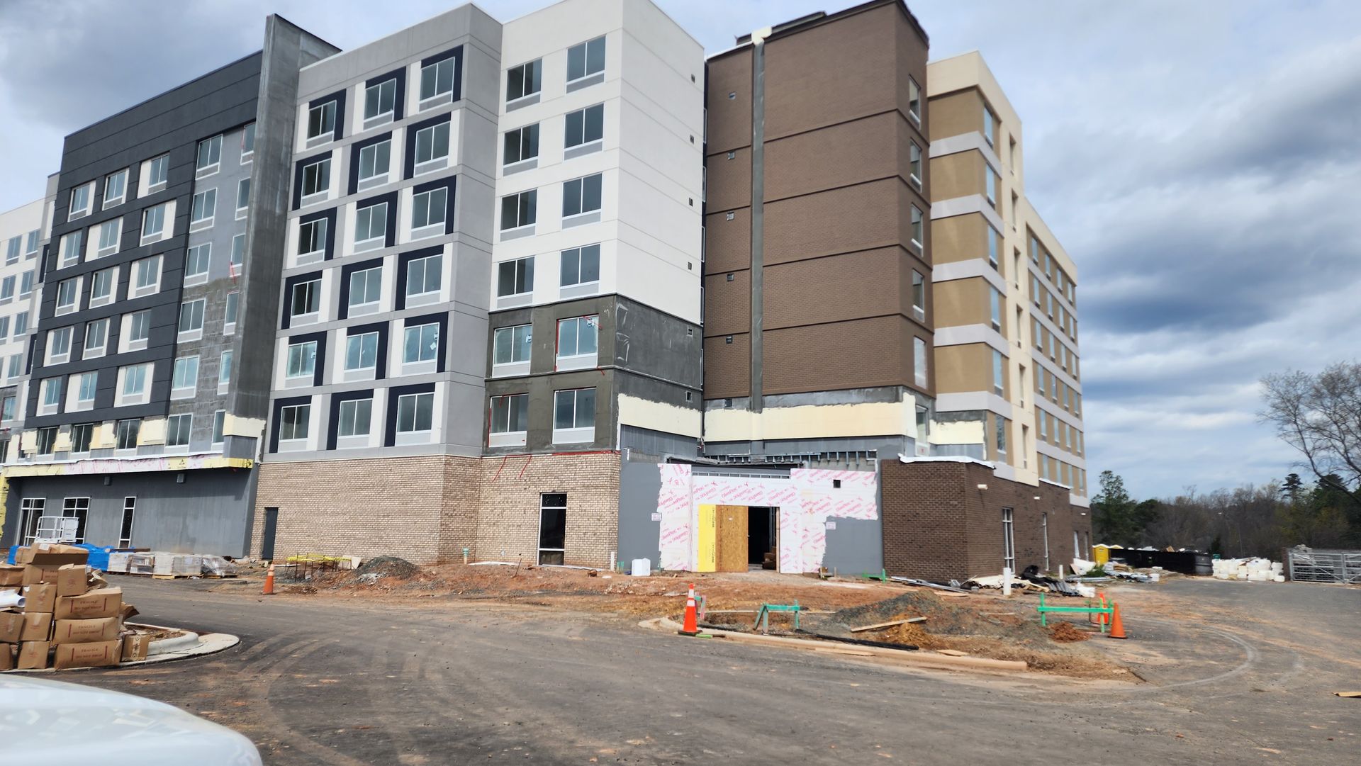Multi-story building under construction with various colors and materials, cloudy sky above.
