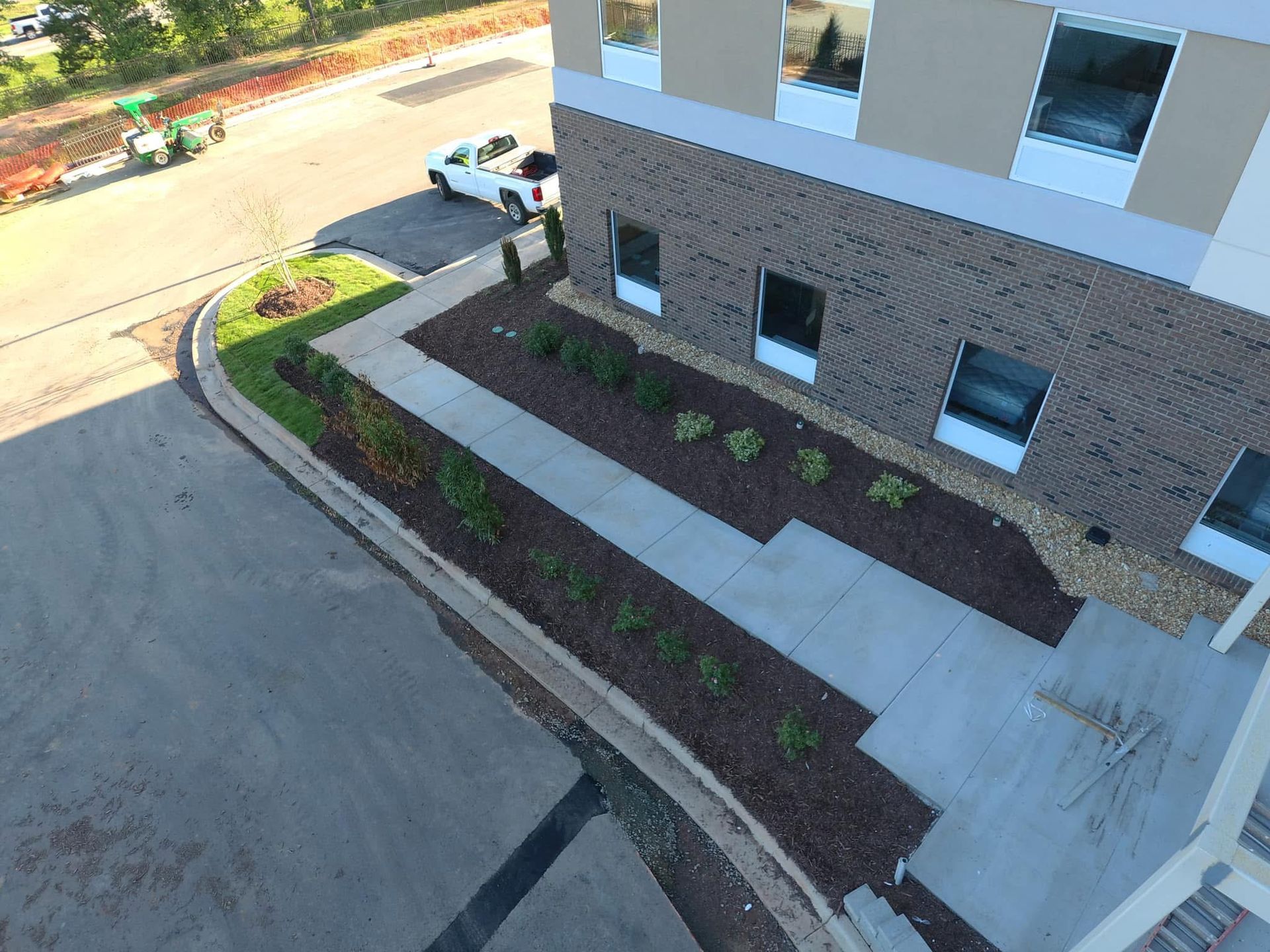 Exterior view of a hotel building with a walkway, landscaping, and a truck parked nearby.