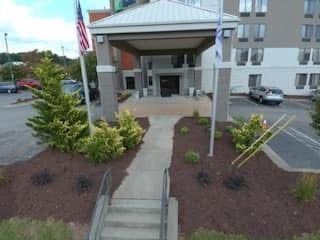 Hotel entrance with walkway, flagpoles, and car parked nearby.