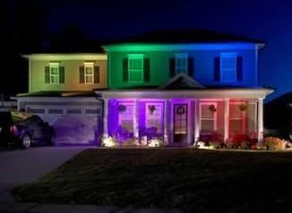 House at night illuminated with colorful lights, including green, blue, purple, and red.