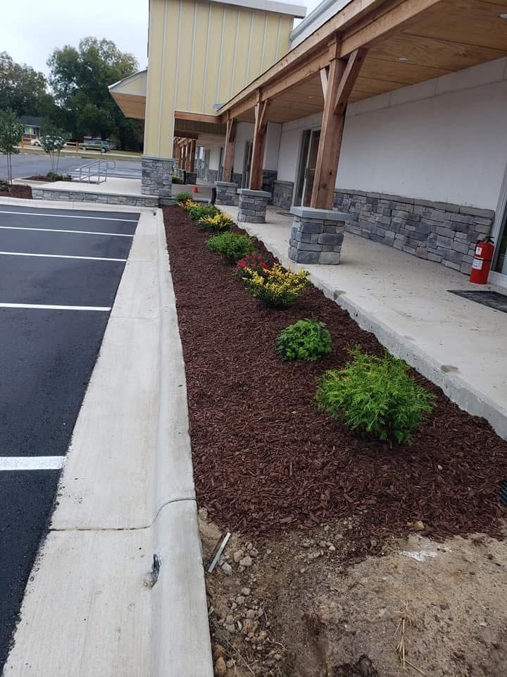 Landscaped flower bed along building with curb and parking lot.