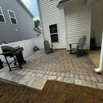 Backyard patio with grill, two chairs, and siding.