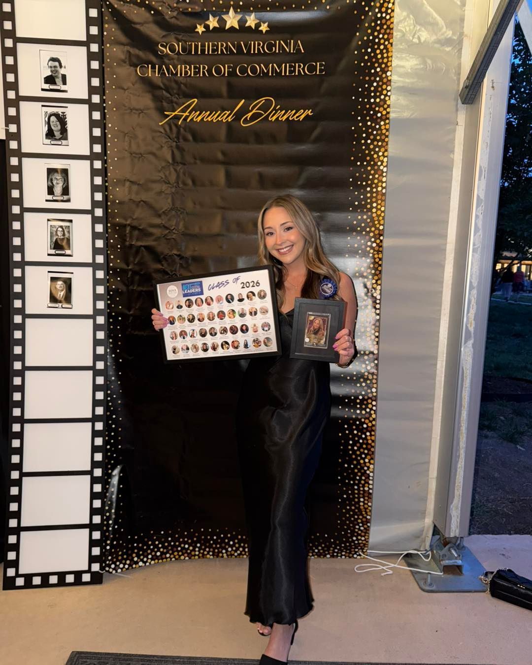 Woman holding an award and sign in front of a black-and-gold event backdrop and filmstrip display