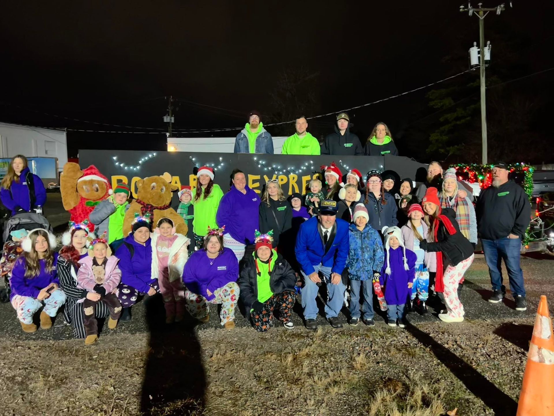 Group poses at night in front of a sign that reads