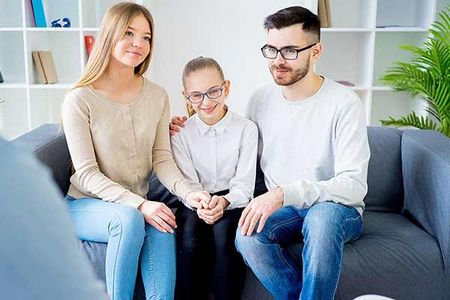 A man and woman are sitting on a couch with a little girl.