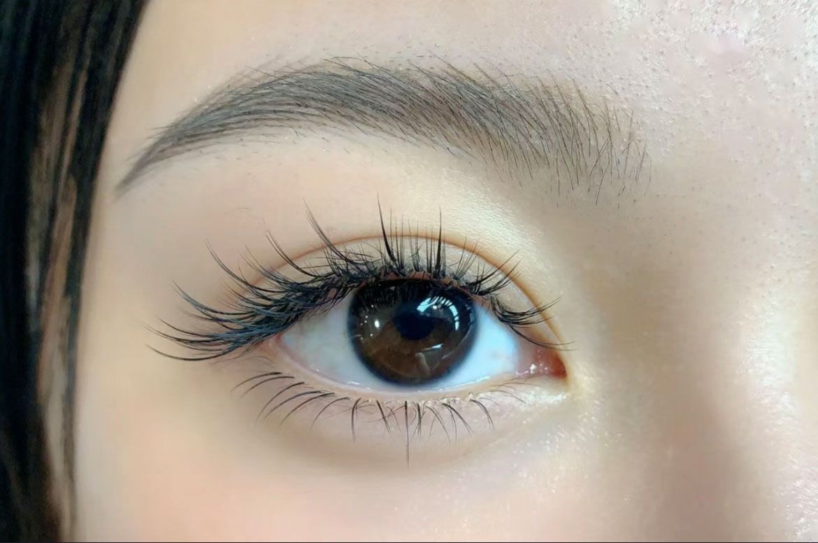 A close up of a woman 's eye with long eyelashes.
