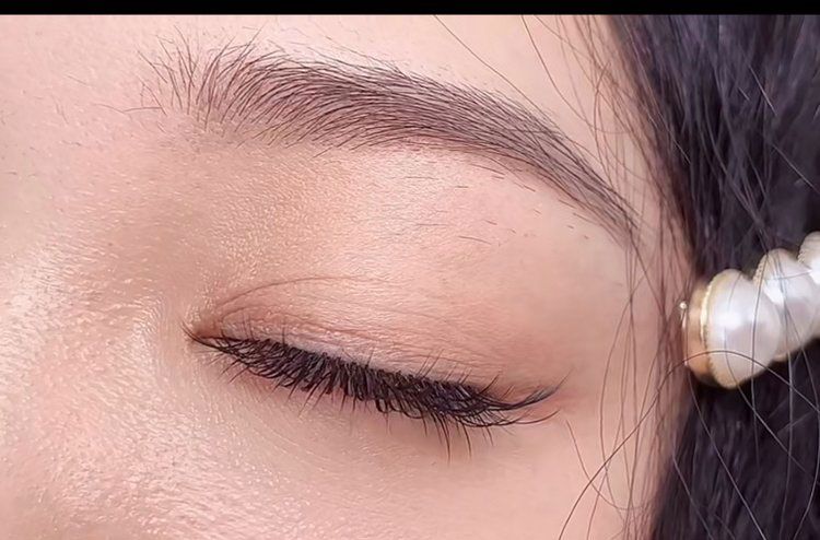 A close up of a woman 's eye with a pearl earring.