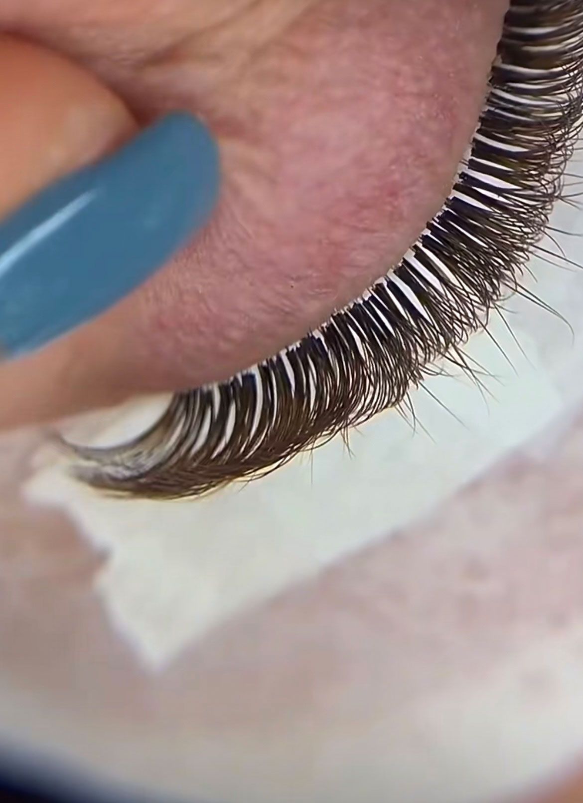 A close up of a person 's eye with blue nails.
