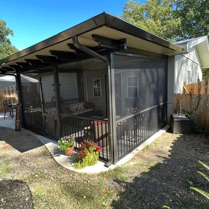 a screened in porch with a pergola and a fence in the backyard of a house