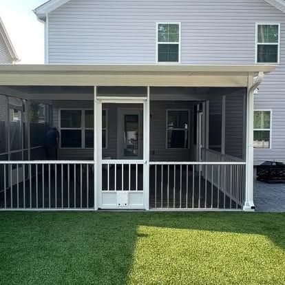 a screened in porch with a white railing is in the backyard of a house