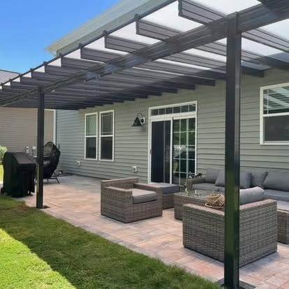 a patio with a pergola and wicker furniture in front of a house
