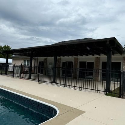a swimming pool in front of a house with a pergola over it