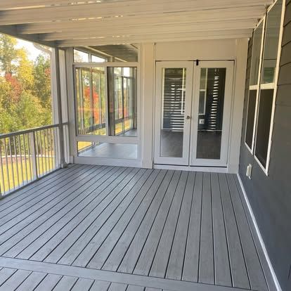 a screened in porch with a gray deck and glass doors