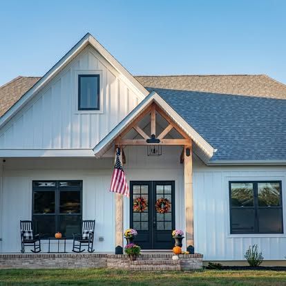 a white house with a gray roof and a porch decorated for fall