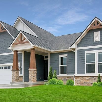 a large house with a gray siding and a white garage door surrounded by a lush green lawn