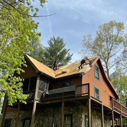 two men are working on the roof of a log cabin