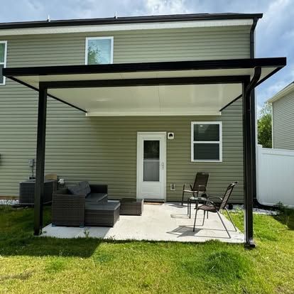 a patio with a couch and chairs under a pergola in the backyard of a house