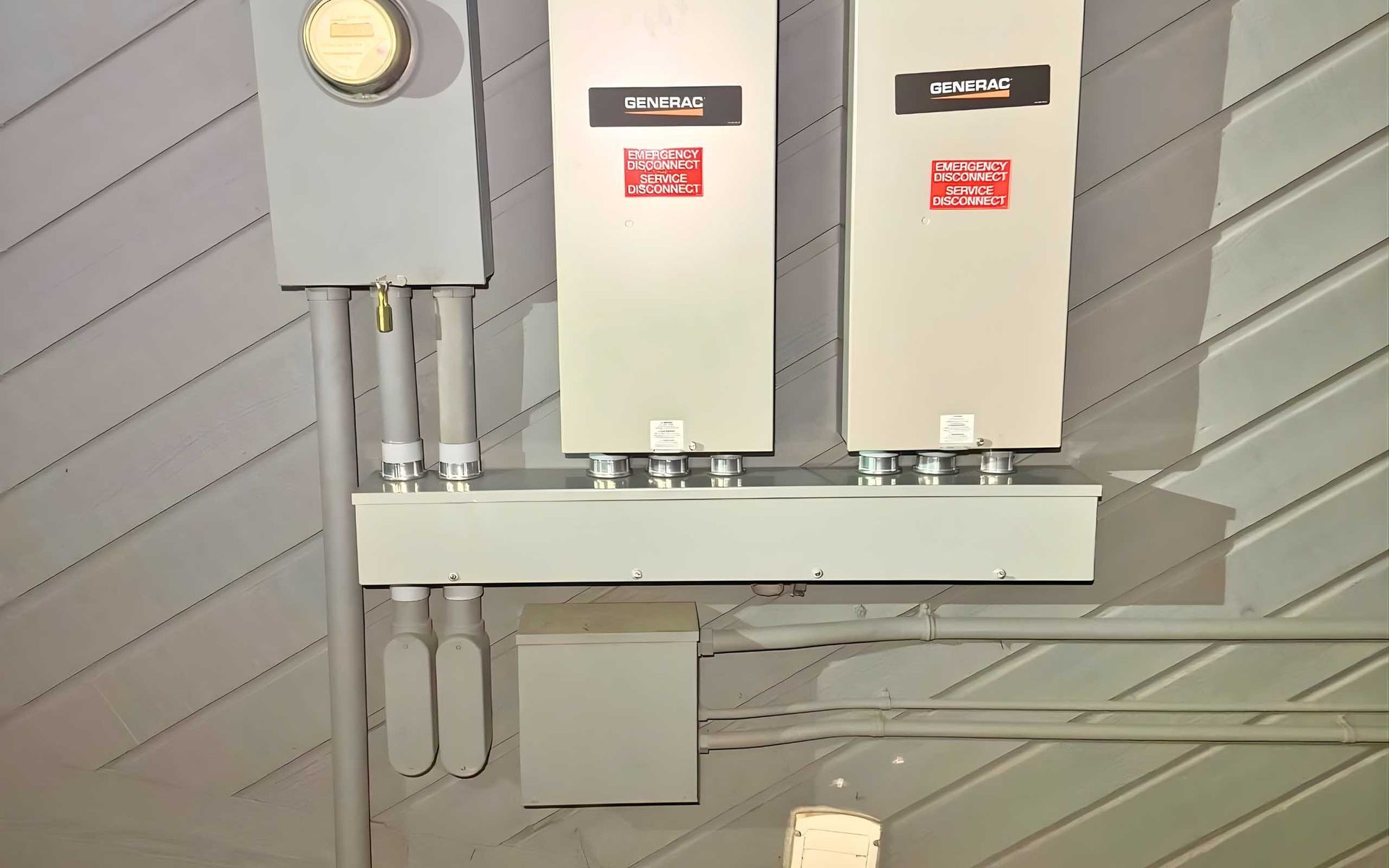 Electrical equipment: meter, inverters, and conduit on a gray wall.
