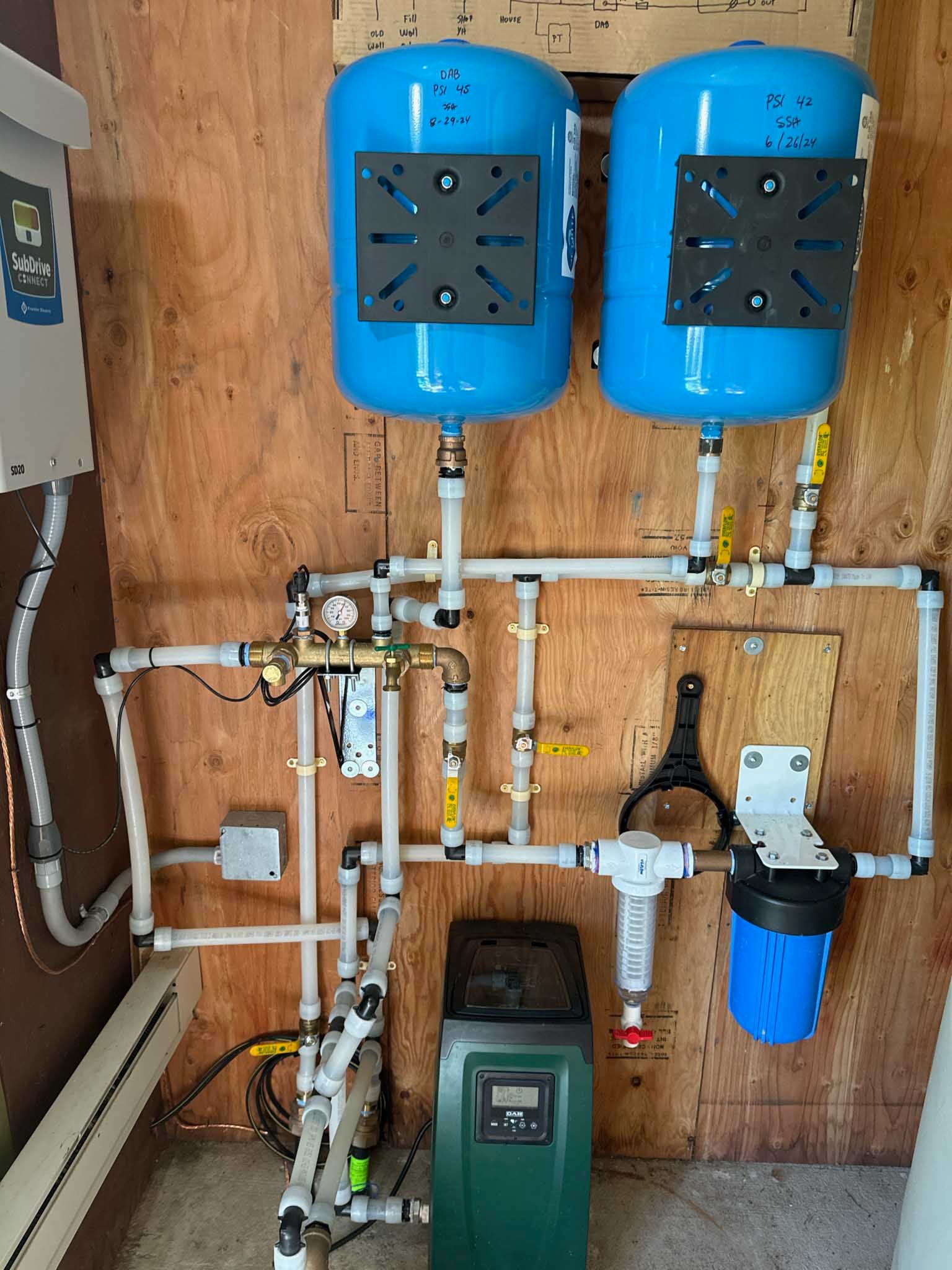 Water filtration and treatment system with blue tanks, pipes, and a green softener.