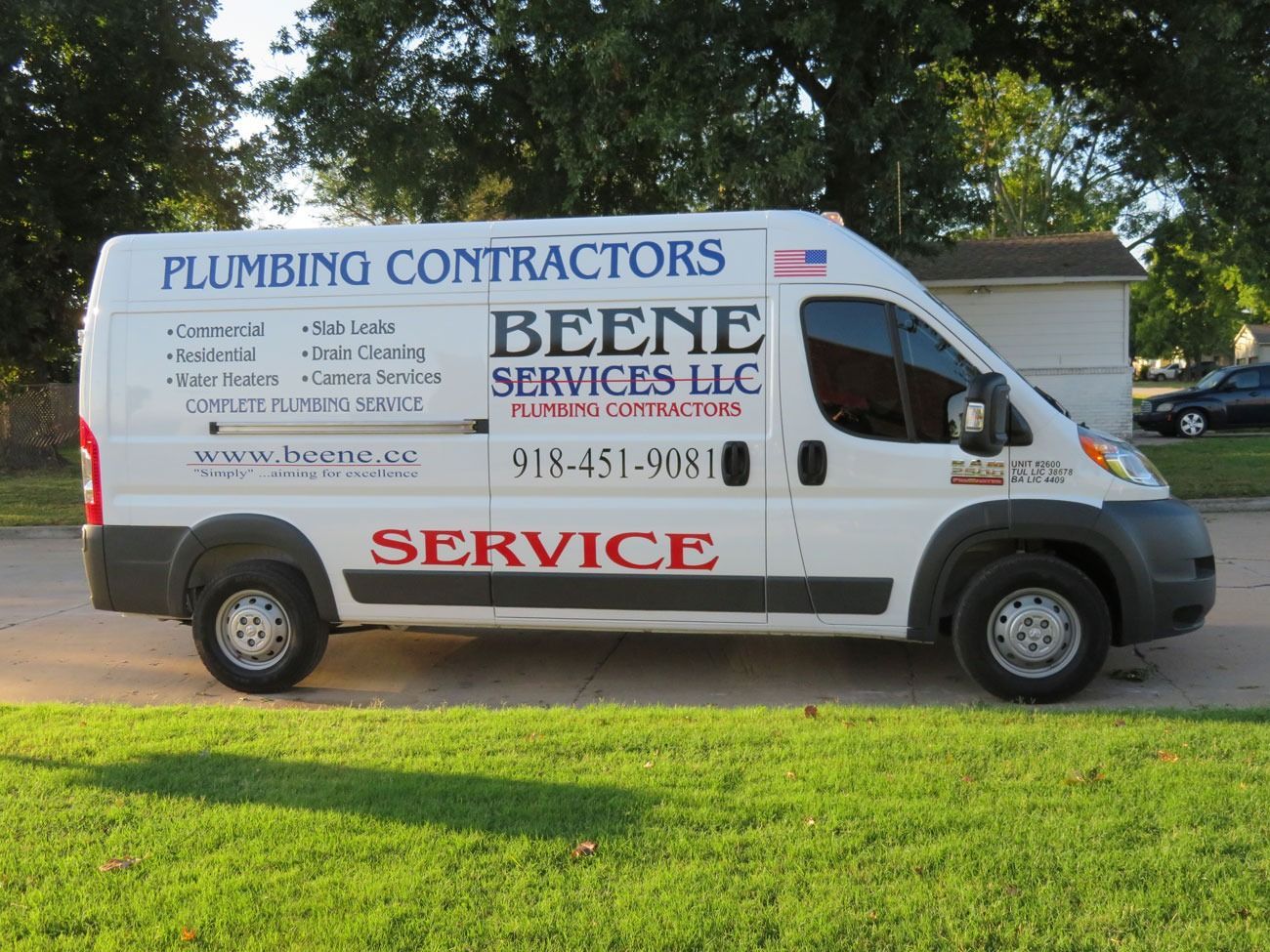 A white van for plumbing contractors is parked in the grass