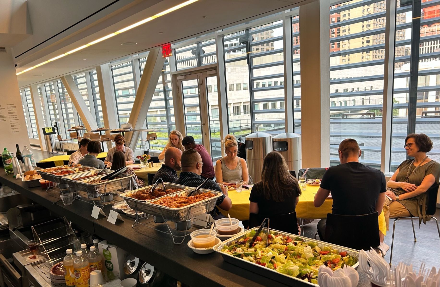 A group of people are sitting at tables in front of a buffet.