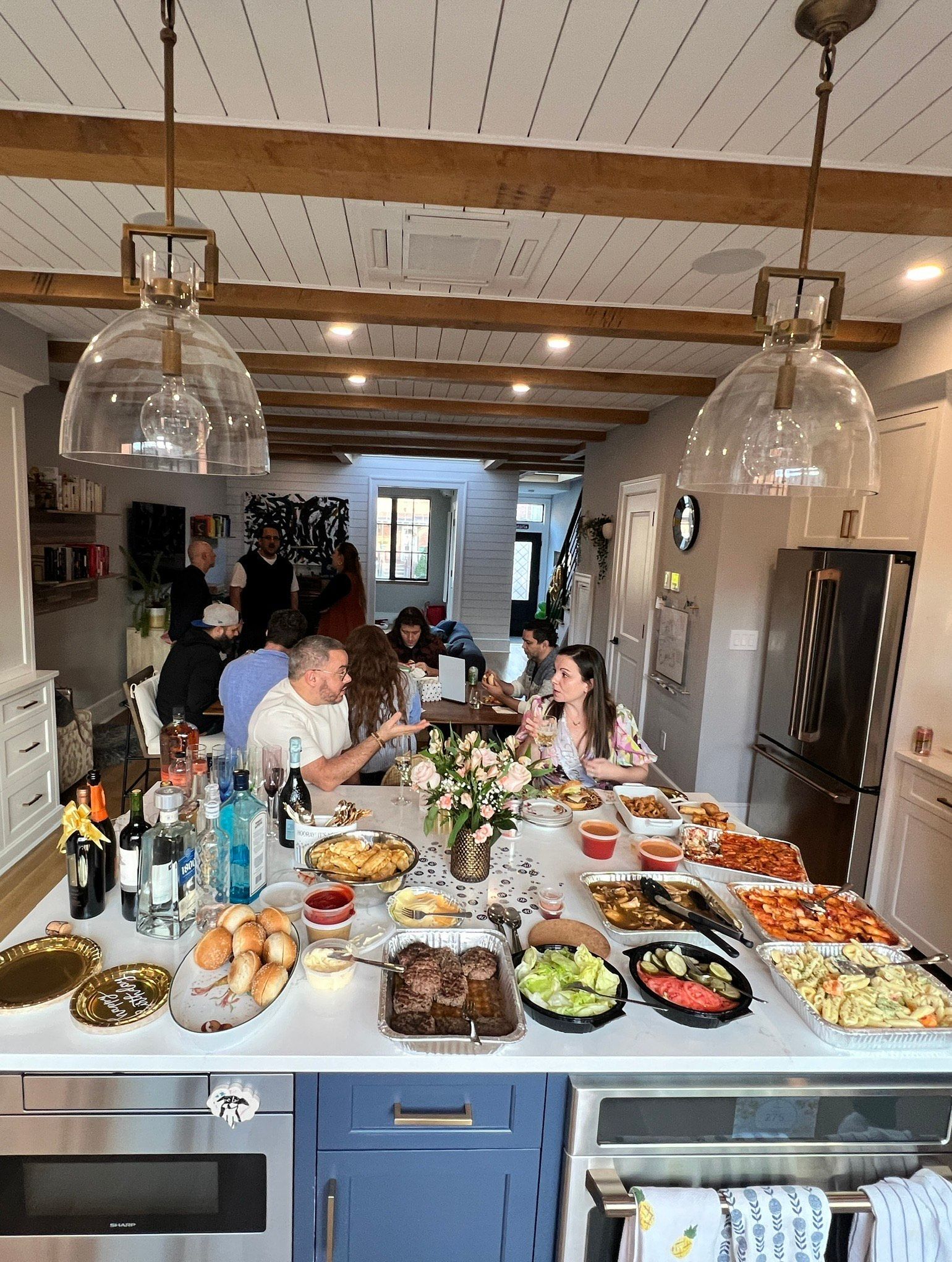 A group of people are sitting at a table in a kitchen eating food.
