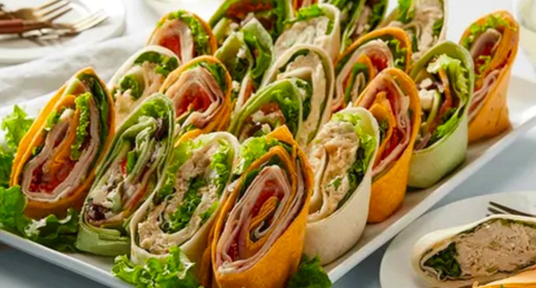 A white plate topped with a variety of wraps on a table.