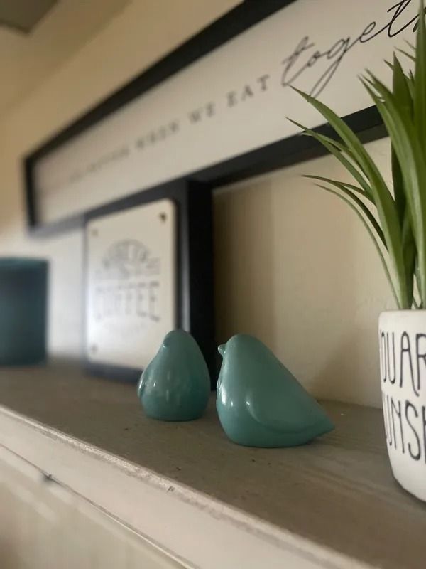 Two teal ceramic birds sit on a shelf, with a 