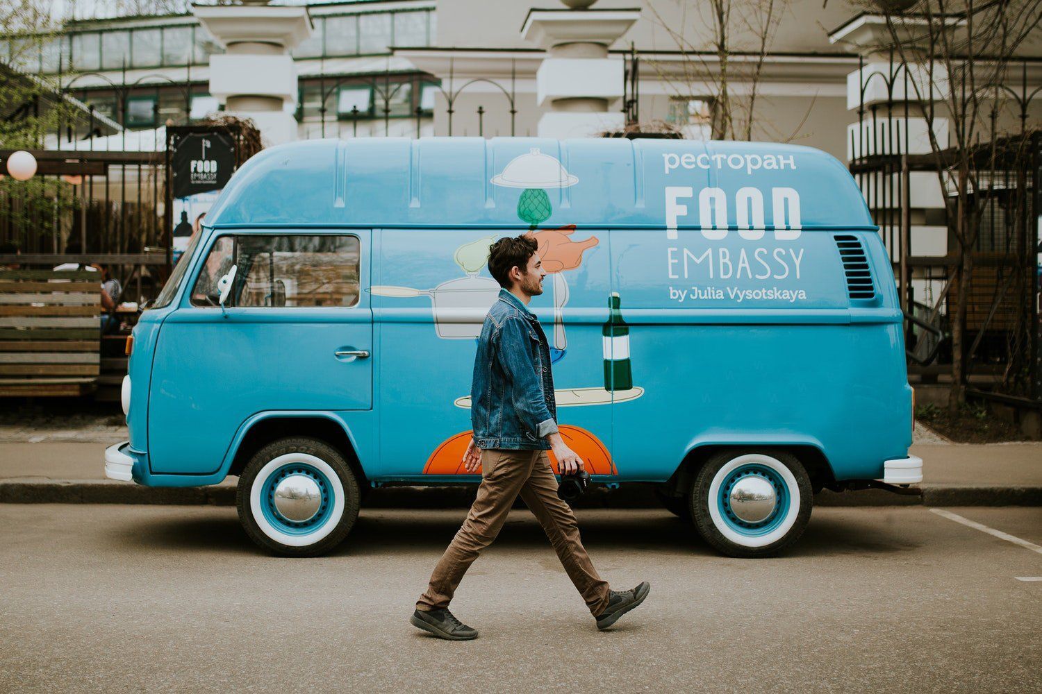 Man walks past a blue VW van food truck with