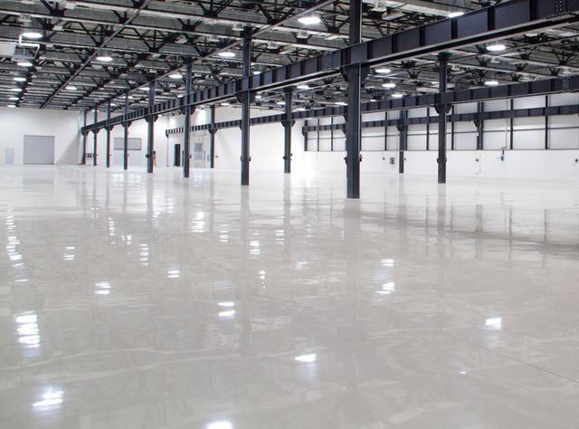 Empty warehouse interior with polished concrete floor and metal beams