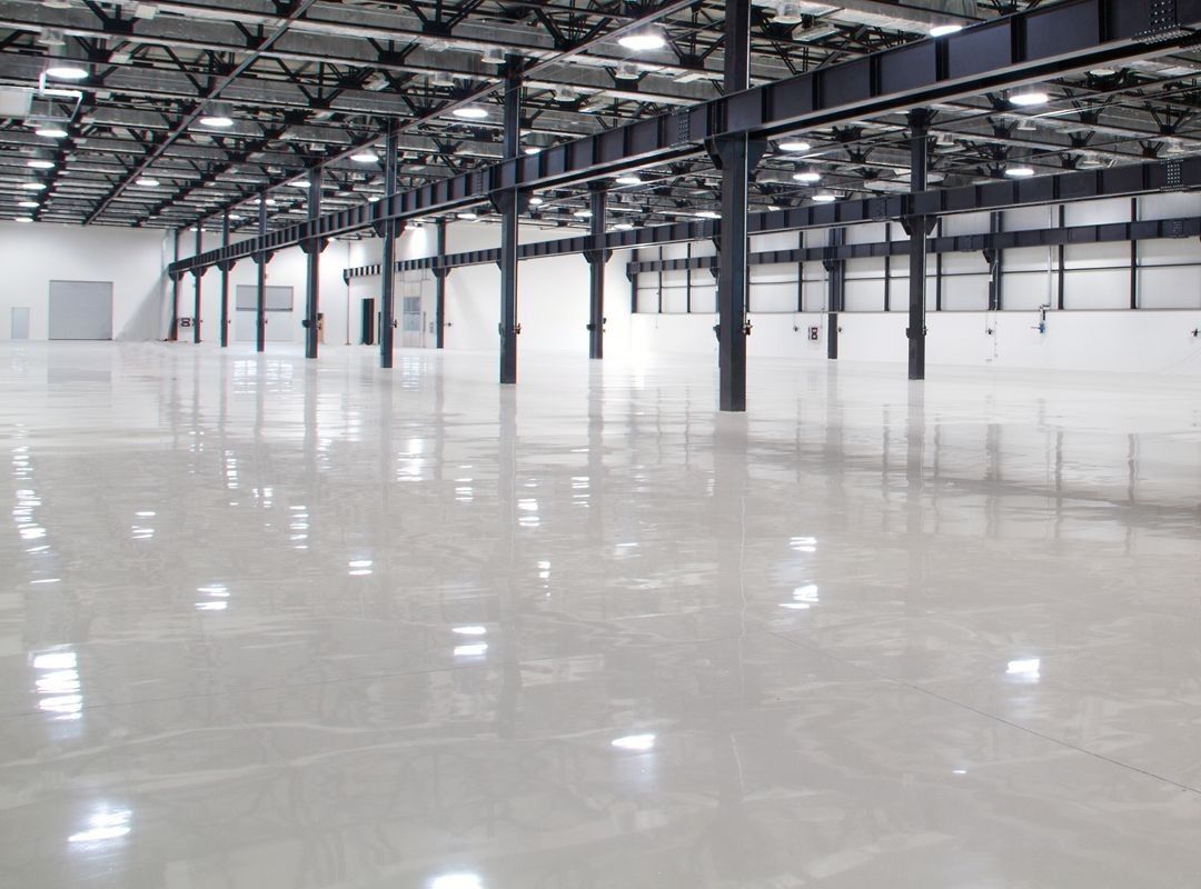 Empty industrial warehouse interior with polished concrete floor and steel support columns