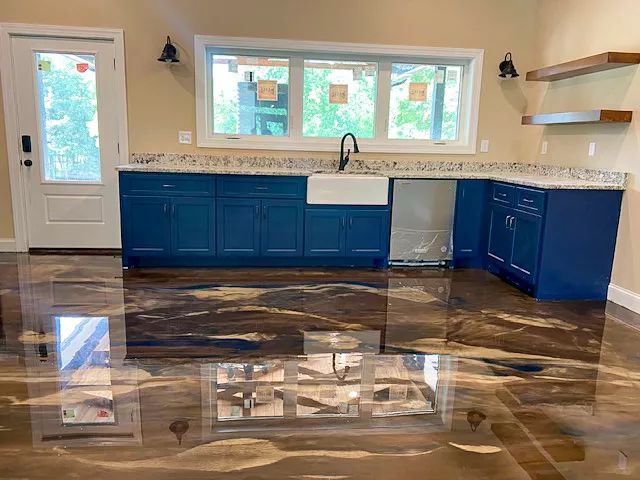 Empty kitchen with blue cabinets, white countertops, and a glossy dark wood floor.