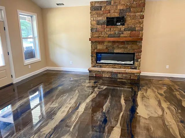 Empty living room with glossy dark hardwood floors, beige walls, a tall brick fireplace, and a small window.