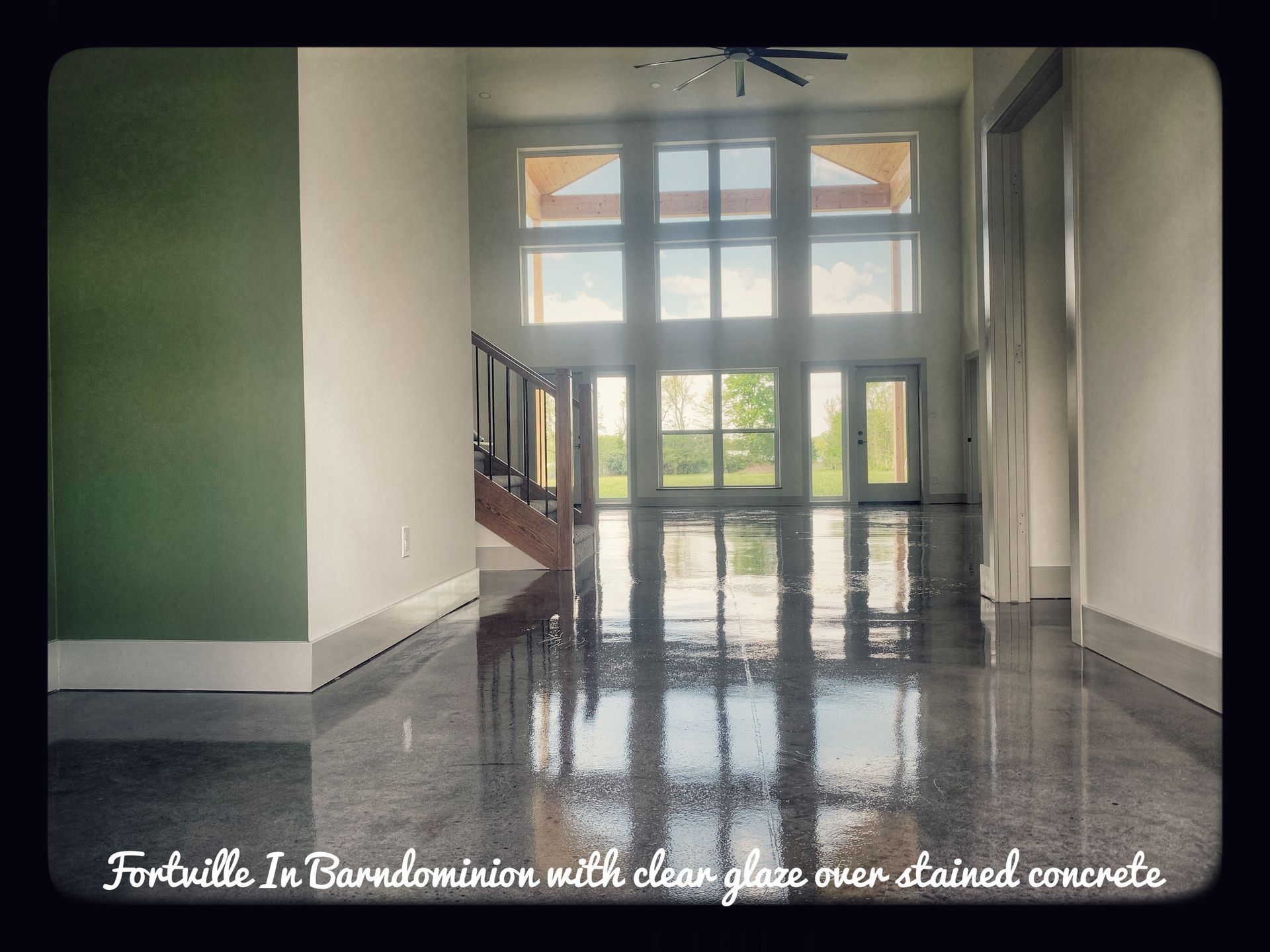 Empty condo entry with glossy concrete floor, white walls, large glass doors, and a staircase.