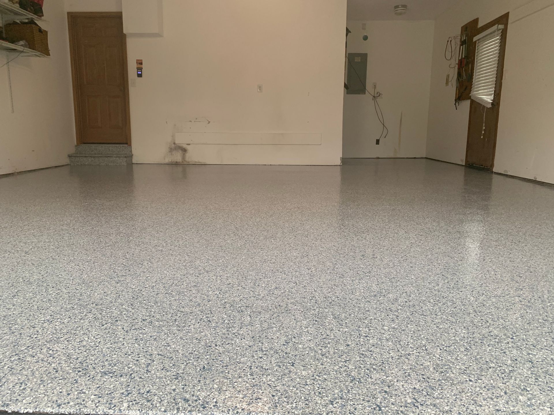 Empty tiled room with beige walls, two wooden doors, and a small window on the right.